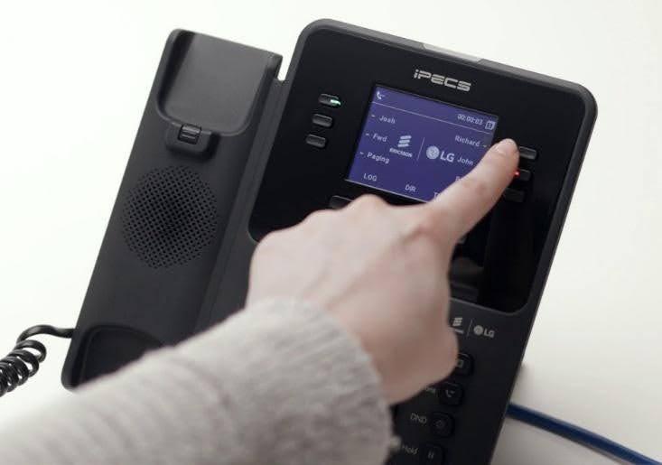 Close-up of a hand dialling a number on a modern black office VoIP handset